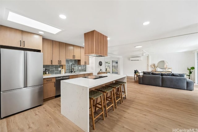 kitchen with light wood-style floors, light countertops, a sink, stainless steel appliances, and a breakfast bar area