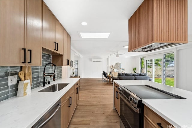 kitchen featuring a wall mounted AC, light countertops, a sink, and appliances with stainless steel finishes