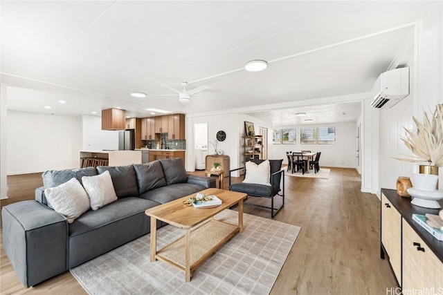 living room featuring a wall mounted air conditioner, a ceiling fan, recessed lighting, light wood finished floors, and baseboards