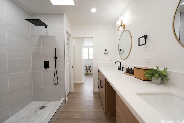 full bath featuring tiled shower, a sink, and wood finished floors