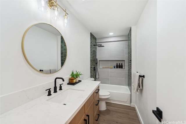 bathroom with vanity, toilet, wood finished floors, shower / bathing tub combination, and baseboards