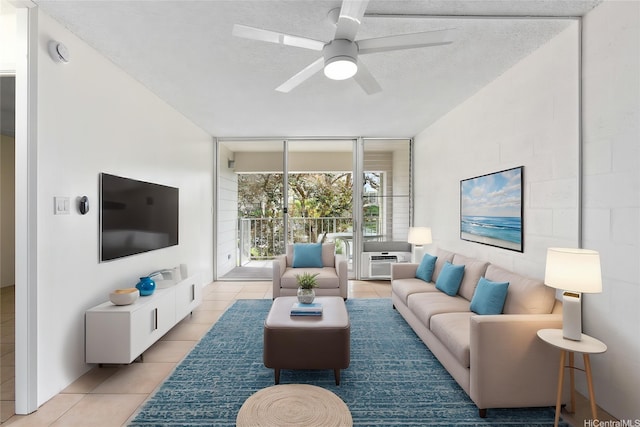 living room with light tile patterned flooring, a ceiling fan, a wall of windows, and a textured ceiling