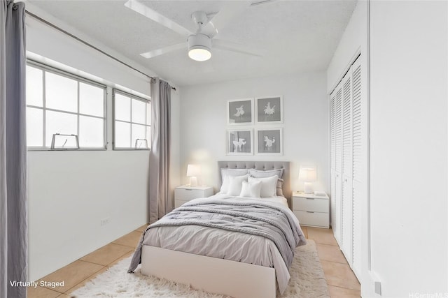 bedroom featuring a closet, a textured ceiling, ceiling fan, and light tile patterned flooring