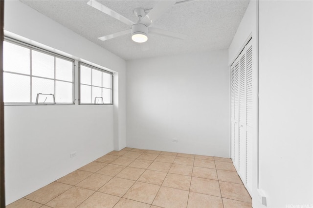 interior space featuring a closet, a textured ceiling, ceiling fan, and light tile patterned floors