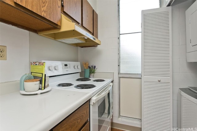 kitchen with under cabinet range hood, brown cabinets, light countertops, and white electric range oven