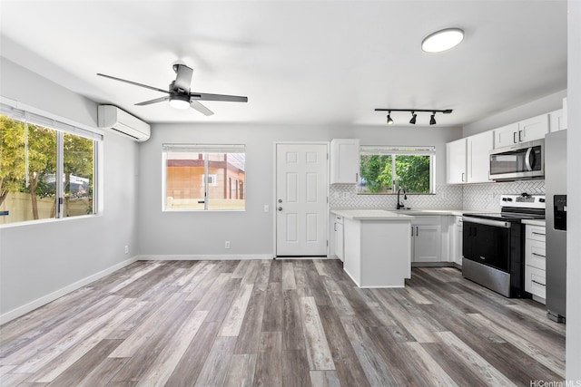 91-241 Makalauna Pl Unit 15, Ewa Beach, HI 96706 - kitchen with stainless steel appliances, light countertops, a wall unit AC, backsplash, and white cabinetry