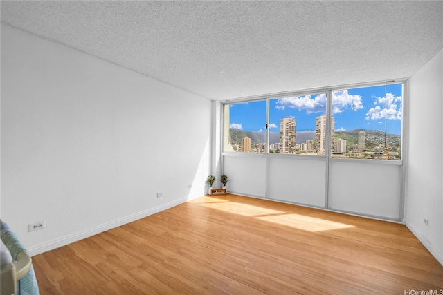 2211 Ala Wai Blvd Unit 1106, Honolulu, HI 96815 - unfurnished room featuring a view of city, a textured ceiling, wood finished floors, and baseboards