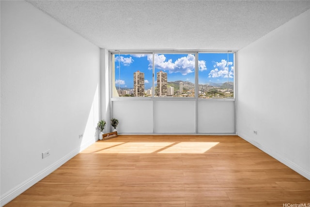 2211 Ala Wai Blvd Unit 1106, Honolulu, HI 96815 - unfurnished room featuring a view of city, wood finished floors, a textured ceiling, and baseboards