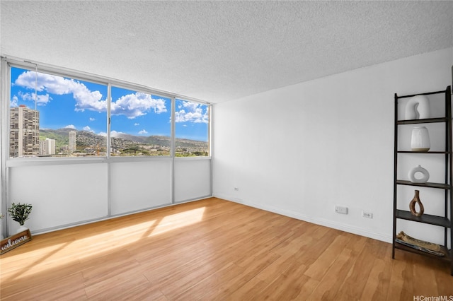 2211 Ala Wai Blvd Unit 1106, Honolulu, HI 96815 - unfurnished room featuring a textured ceiling, wood finished floors, baseboards, and a city view