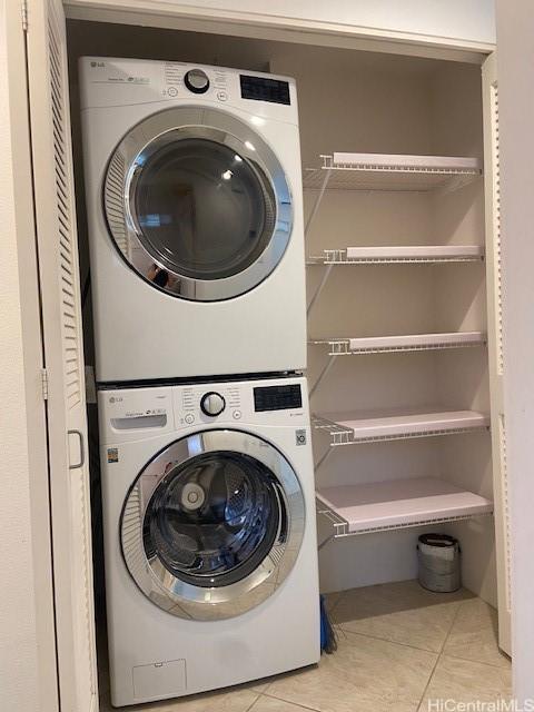 washroom with tile patterned floors, stacked washing maching and dryer, and laundry area