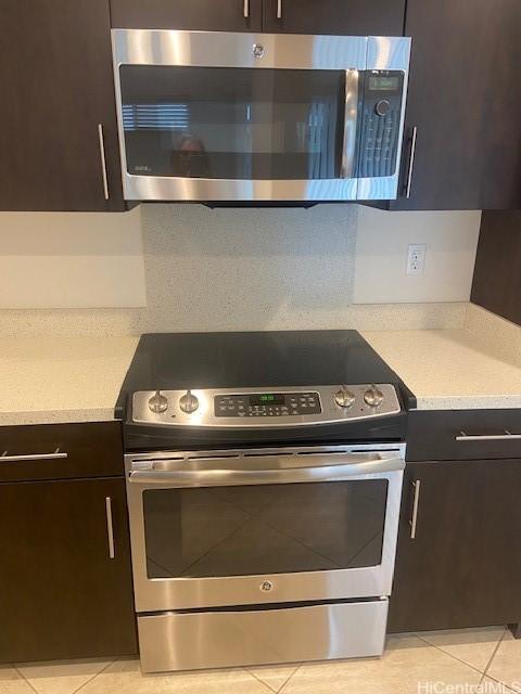 kitchen featuring dark brown cabinets, stainless steel appliances, light countertops, and light tile patterned floors