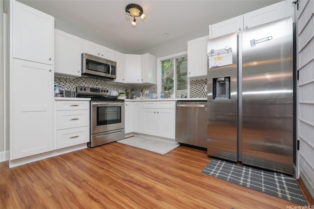 kitchen featuring stainless steel appliances, light wood-type flooring, backsplash, and white cabinetry