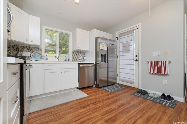kitchen featuring appliances with stainless steel finishes, light wood-type flooring, decorative backsplash, and light countertops