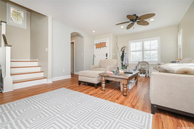 living area featuring arched walkways, wood finished floors, a ceiling fan, stairway, and recessed lighting