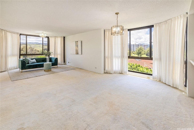 5090 Likini St Unit 501, Honolulu, HI 96818 - unfurnished living room featuring a wall of windows, a chandelier, healthy amount of natural light, carpet, and a textured ceiling