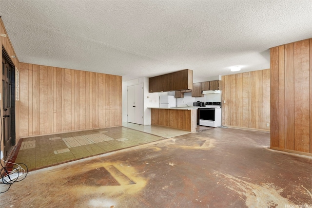 kitchen featuring open floor plan, wood walls, white appliances, concrete floors, and under cabinet range hood