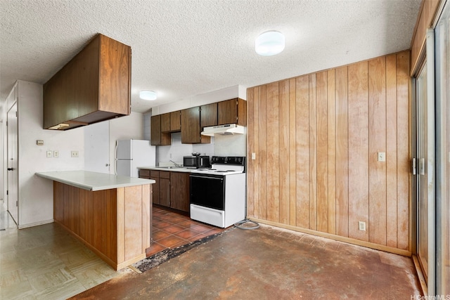 kitchen featuring a peninsula, a textured ceiling, white appliances, wooden walls, and under cabinet range hood