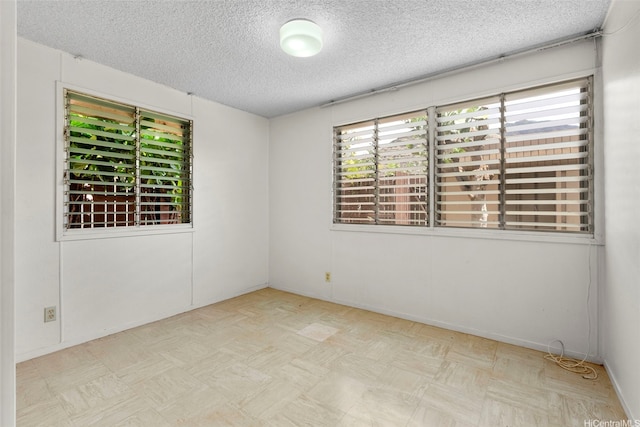 unfurnished room with baseboards and a textured ceiling