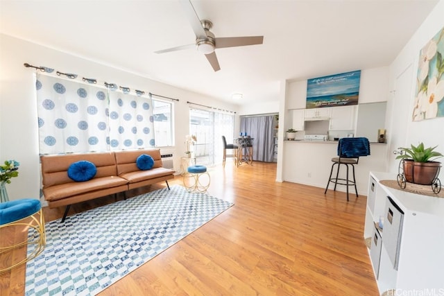 living area featuring light wood-type flooring and a ceiling fan