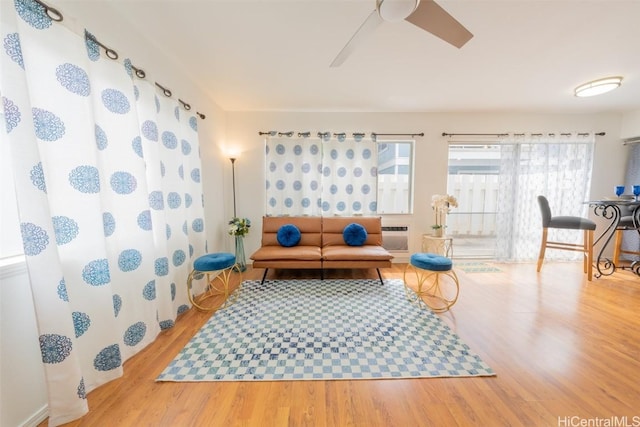 living area with wood finished floors, a ceiling fan, and an AC wall unit