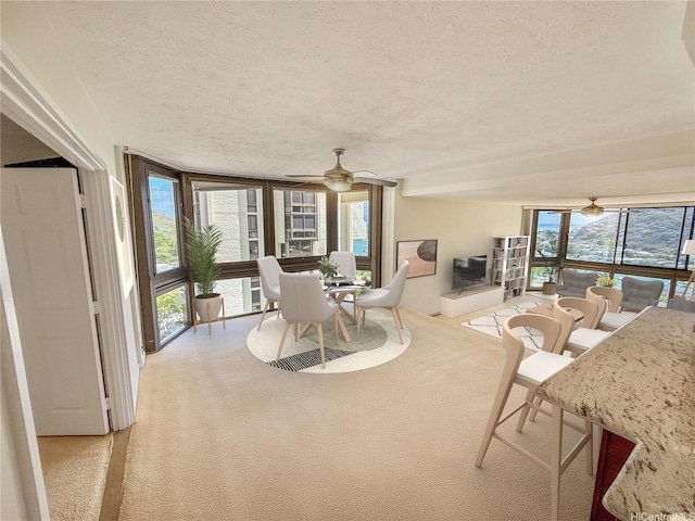 521 Hahaione St Unit 2-15L, Honolulu, HI 96825 - dining room with a textured ceiling, light carpet, a ceiling fan, and a wall of windows