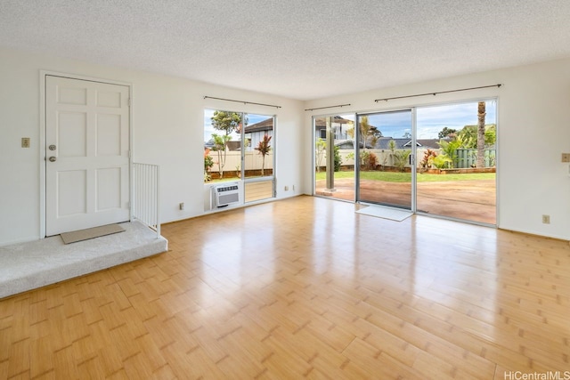 94-1199 Meleinoa Pl Unit 21C, Waipahu, HI 96797 - spare room with a textured ceiling, a wall unit AC, and light wood-style floors