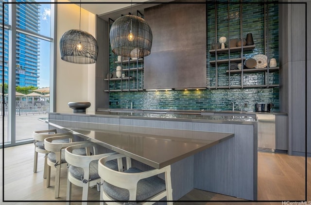 bar featuring backsplash, light wood-style floors, indoor wet bar, and a sink