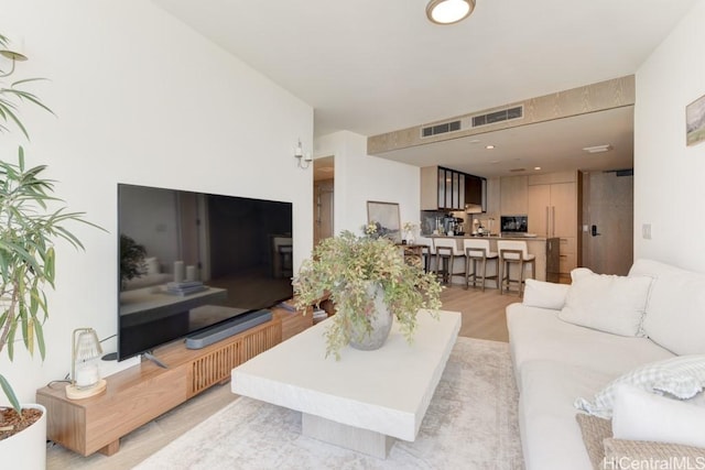living area with light wood-style floors and visible vents