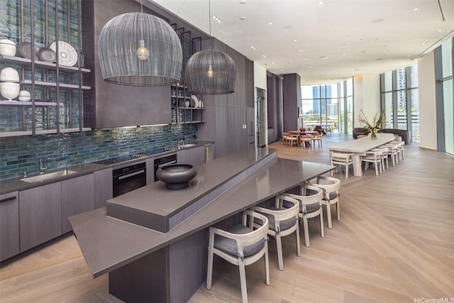 kitchen featuring dark countertops, a sink, floor to ceiling windows, black appliances, and modern cabinets