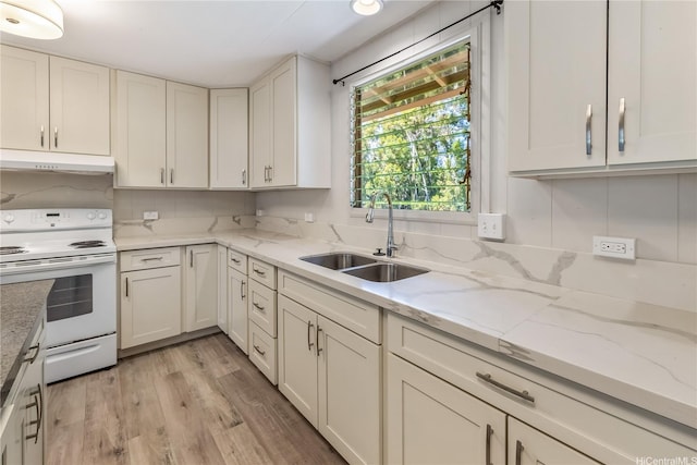 kitchen with a sink, under cabinet range hood, light wood finished floors, white cabinetry, and electric range