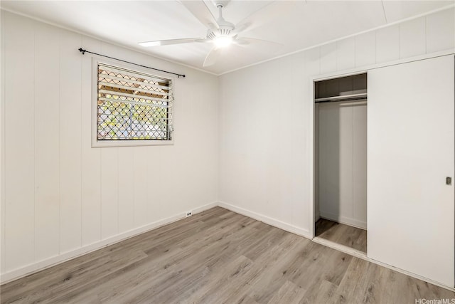 unfurnished bedroom with wood finished floors, a closet, a ceiling fan, and baseboards
