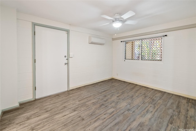 empty room with ceiling fan, wood finished floors, and a wall mounted air conditioner