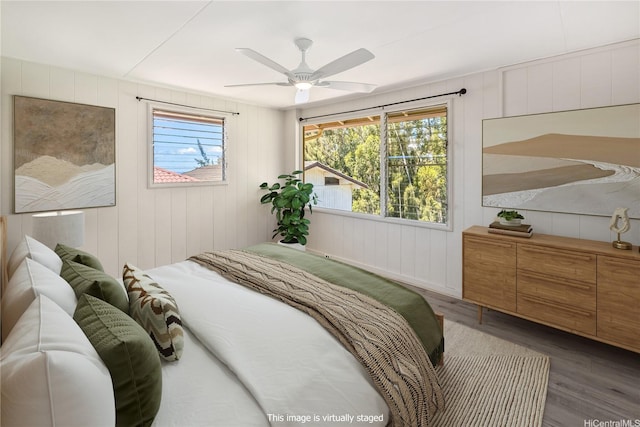bedroom with wood walls, ceiling fan, and wood finished floors
