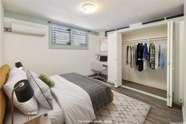 bedroom featuring a closet, a wall unit AC, and wood finished floors