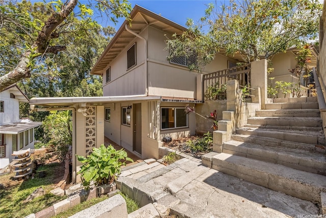 view of front of home featuring stucco siding and stairs