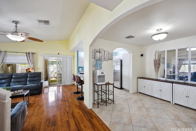 living area with visible vents, a ceiling fan, arched walkways, and a healthy amount of sunlight