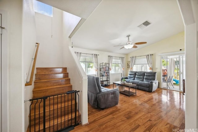 living room with vaulted ceiling, a ceiling fan, stairs, visible vents, and wood finished floors