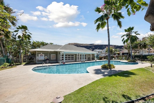 pool with a patio, a yard, and fence