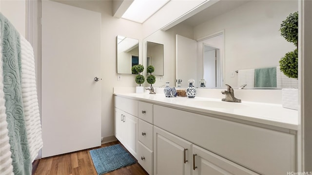 full bathroom featuring a sink, double vanity, and wood finished floors