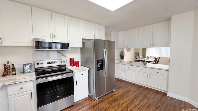 kitchen with dark wood-type flooring, appliances with stainless steel finishes, white cabinetry, and light stone countertops
