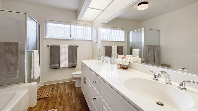 full bath with a shower stall, wood finished floors, double vanity, and a sink