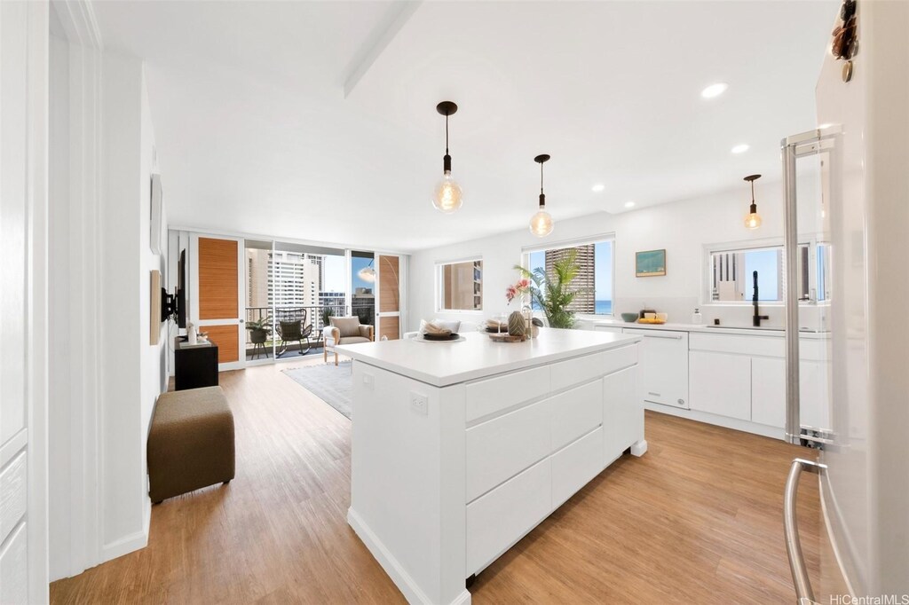 400 Hobron Ln Unit 1601, Honolulu, HI 96815 - kitchen with light wood-type flooring, open floor plan, a kitchen island, white cabinets, and a sink