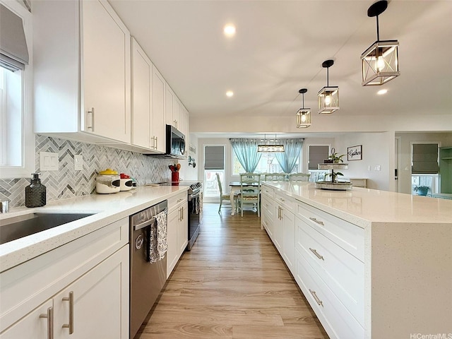 kitchen with white cabinets, appliances with stainless steel finishes, a healthy amount of sunlight, and tasteful backsplash