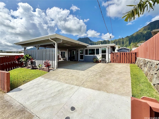 rear view of property featuring driveway, a gate, fence, a mountain view, and an attached carport