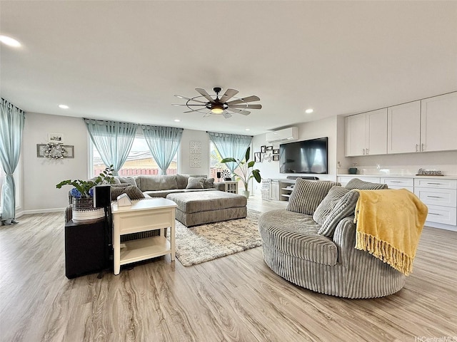 living room featuring a wall unit AC, a ceiling fan, recessed lighting, and light wood-style flooring
