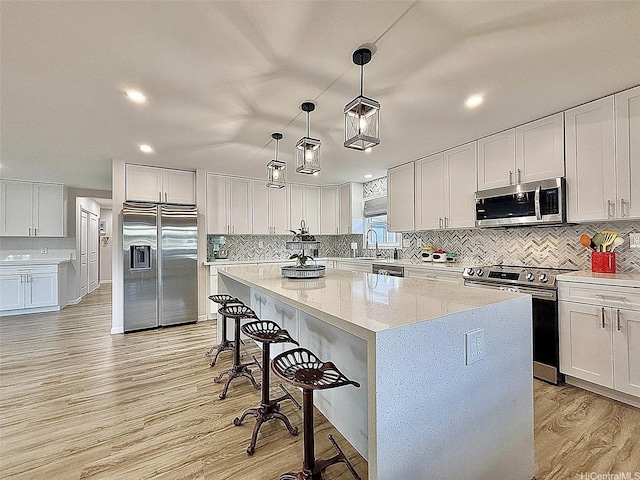 kitchen featuring a breakfast bar area, appliances with stainless steel finishes, tasteful backsplash, a center island, and light wood-type flooring