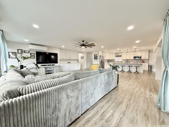 living area featuring recessed lighting, a wall mounted air conditioner, light wood finished floors, and a ceiling fan