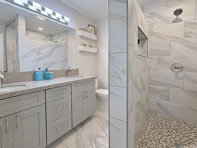 full bath with double vanity, a sink, marble finish floor, and tiled shower