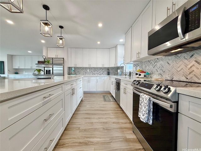 kitchen with pendant lighting, light stone countertops, white cabinets, tasteful backsplash, and appliances with stainless steel finishes