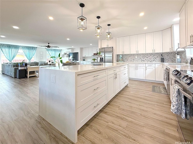 kitchen with a sink, light wood-style floors, backsplash, and stainless steel appliances